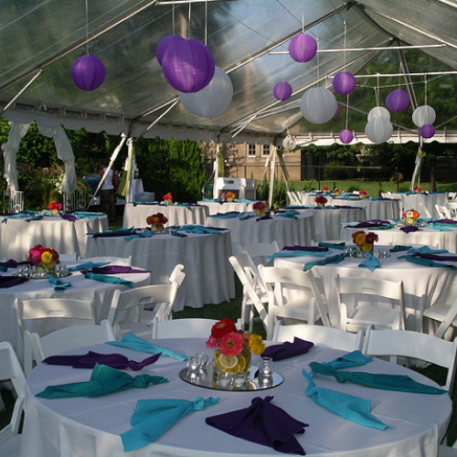 Table and chairs set up under an event tent outside