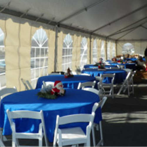 Table and chairs set up under an event tent outside