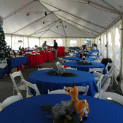 Table and chairs set up under an event tent outside