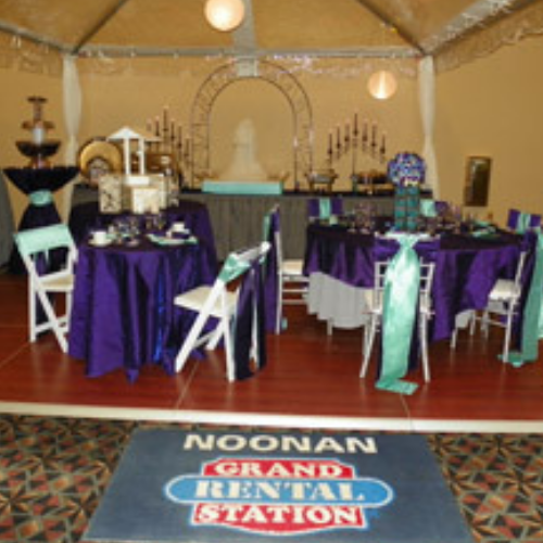 Table and chairs set up under an event tent outside