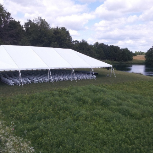 Table and chairs set up under an event tent outside