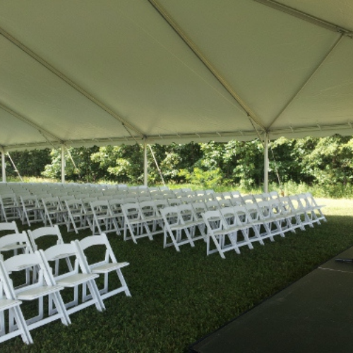 Chairs set up under an event tent outside