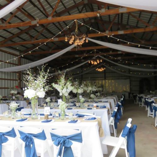 Table and chairs set up under an event tent outside