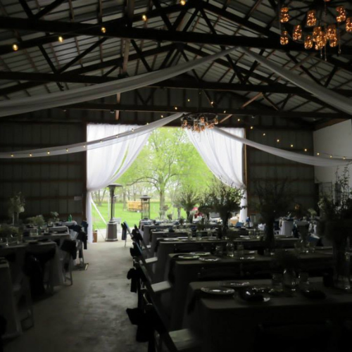 Table and chairs set up under an event tent outside