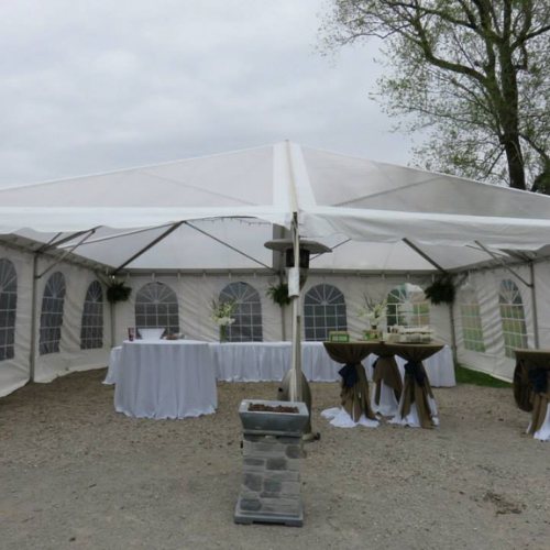 Table and chairs set up under an event tent outside