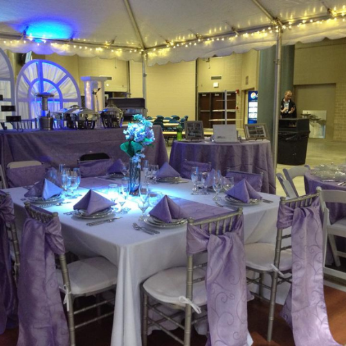Table and chairs set up under an event tent outside