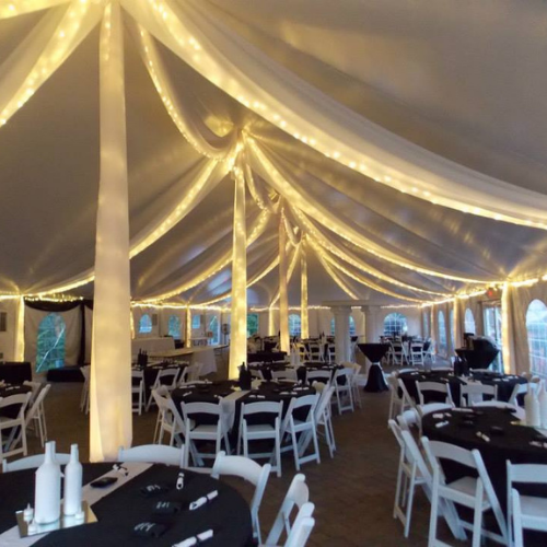 Table and chairs set up under an event tent outside