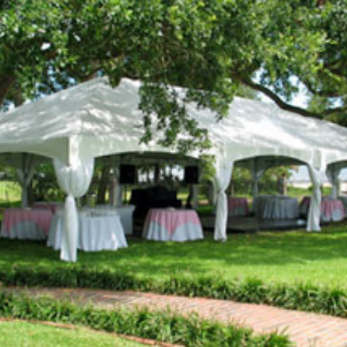 Table and chairs set up under an event tent outside