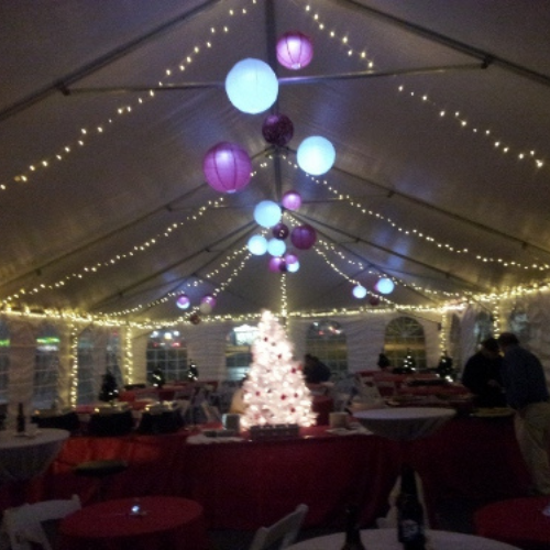 Table and chairs set up under an event tent outside