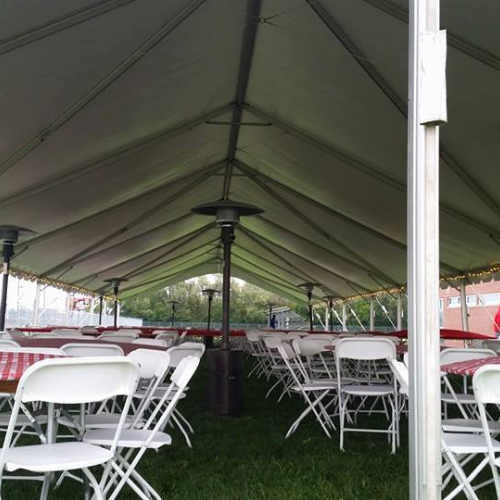 Table and chairs set up under an event tent outside