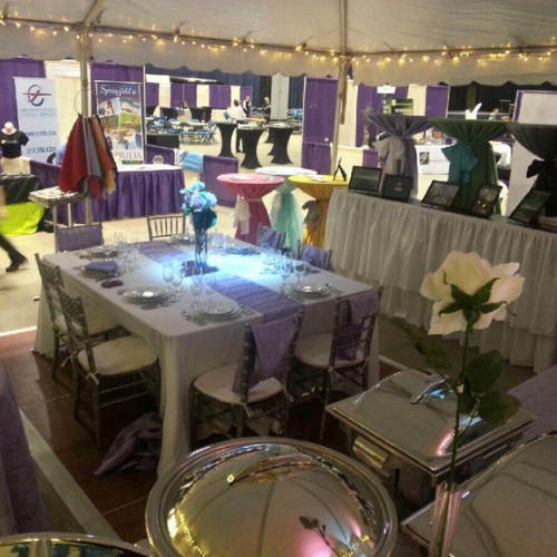 Table and chairs set up under an event tent outside