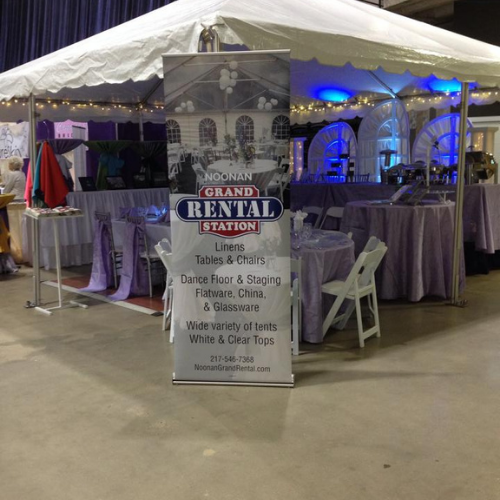 Table and chairs set up under an event tent outside