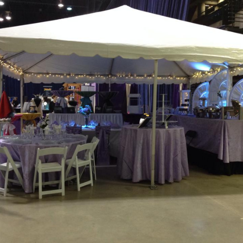 Table and chairs set up under an event tent outside