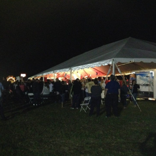 Table and chairs set up under an event tent outside