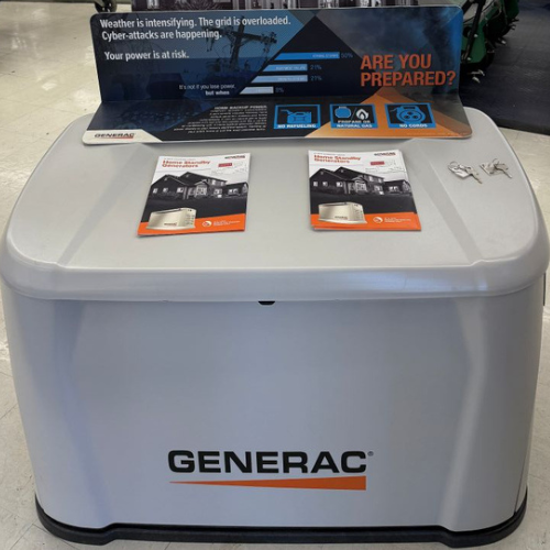Display of a Generac generator with brochures on top. A sign warns of intensified weather and grid overload, prompting preparation.