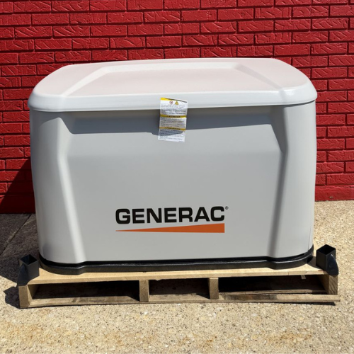 A Generac generator sits on a wooden pallet against a vibrant red brick wall. The white unit has the brand logo prominently displayed on the front.